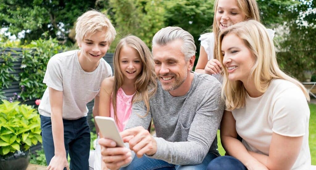 Familienmoment im Garten mit gemeinsamer Smartphone-Nutzung – HotSpring