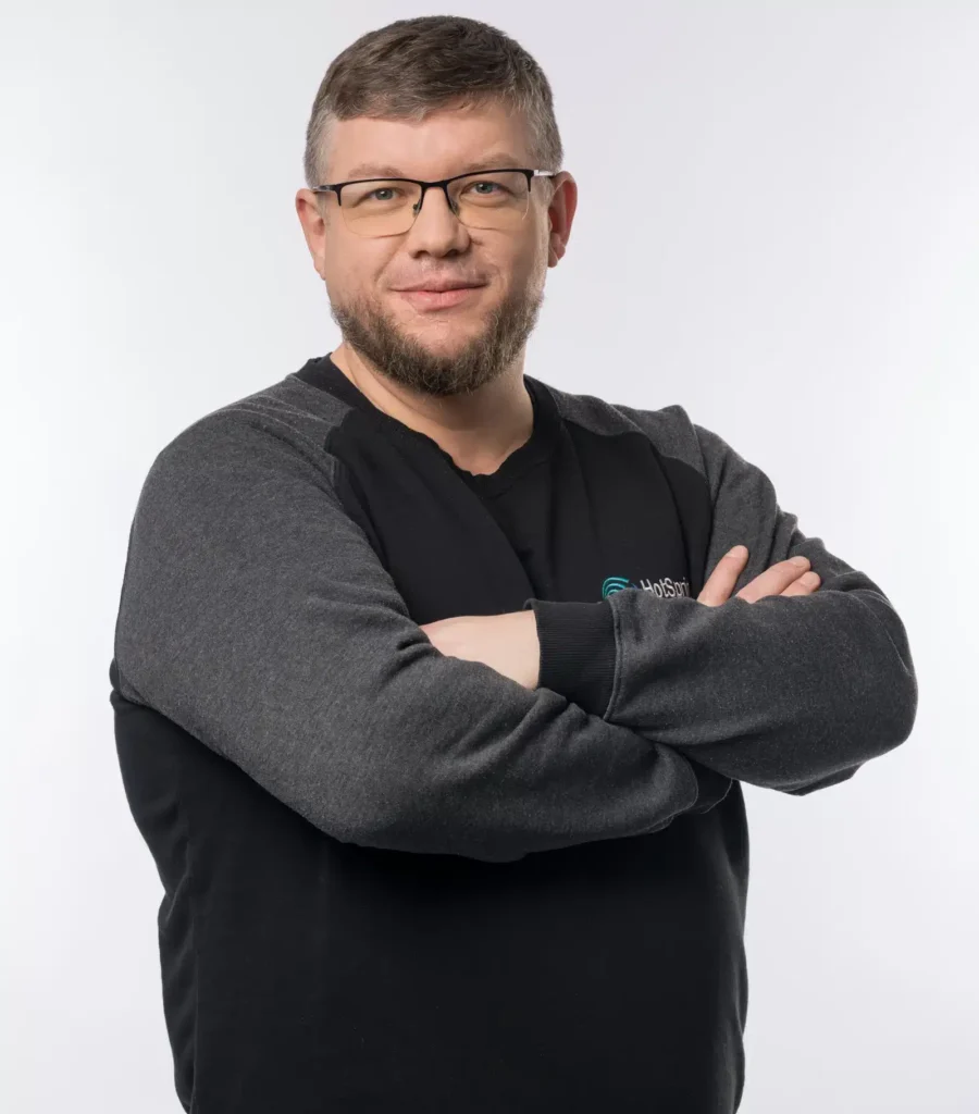 Mann mit Brille und verschränkten Armen lächelt in die Kamera – professionelles Porträtfoto für das HotSpring Team