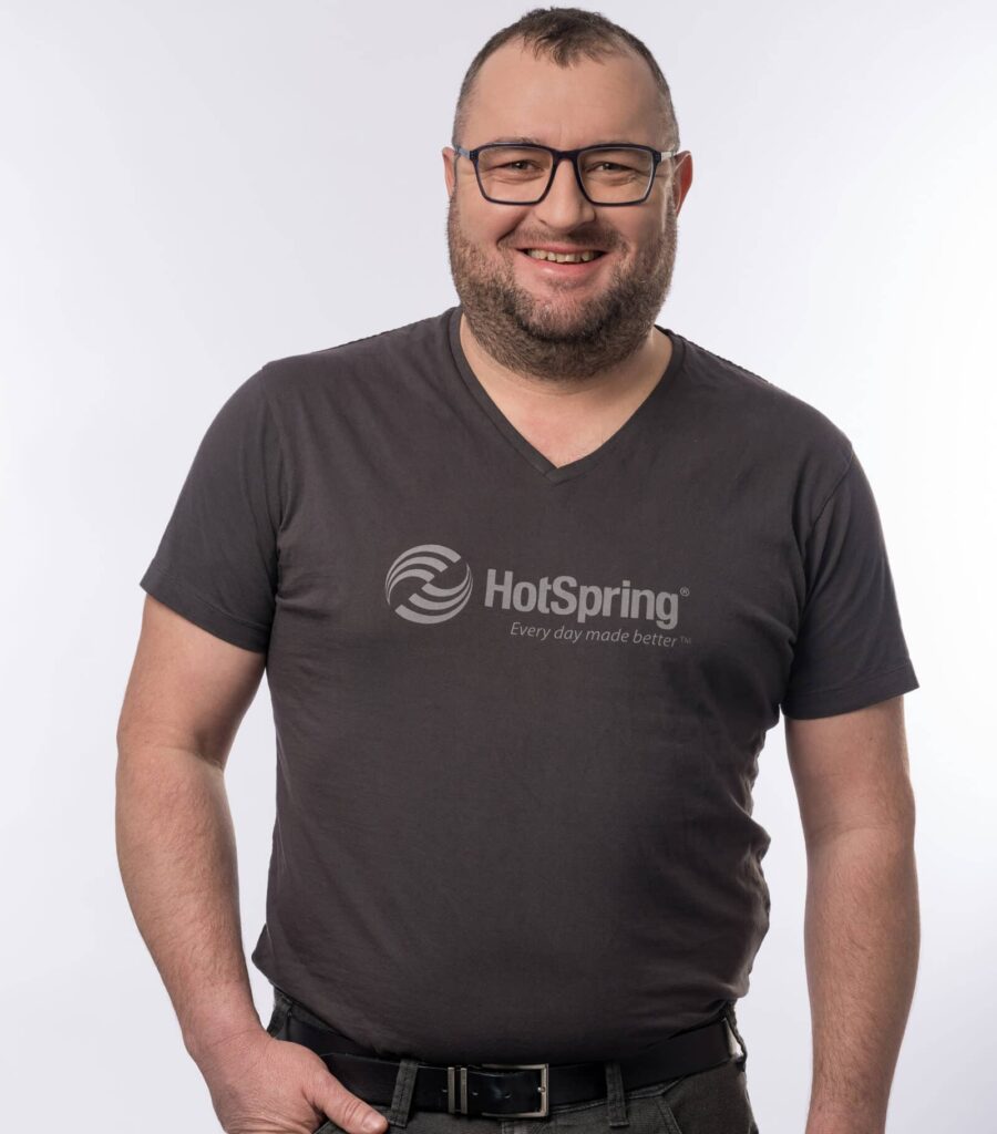 Mann mit HotSpring T-Shirt lächelt in die Kamera – Porträtfoto für das HotSpring Team